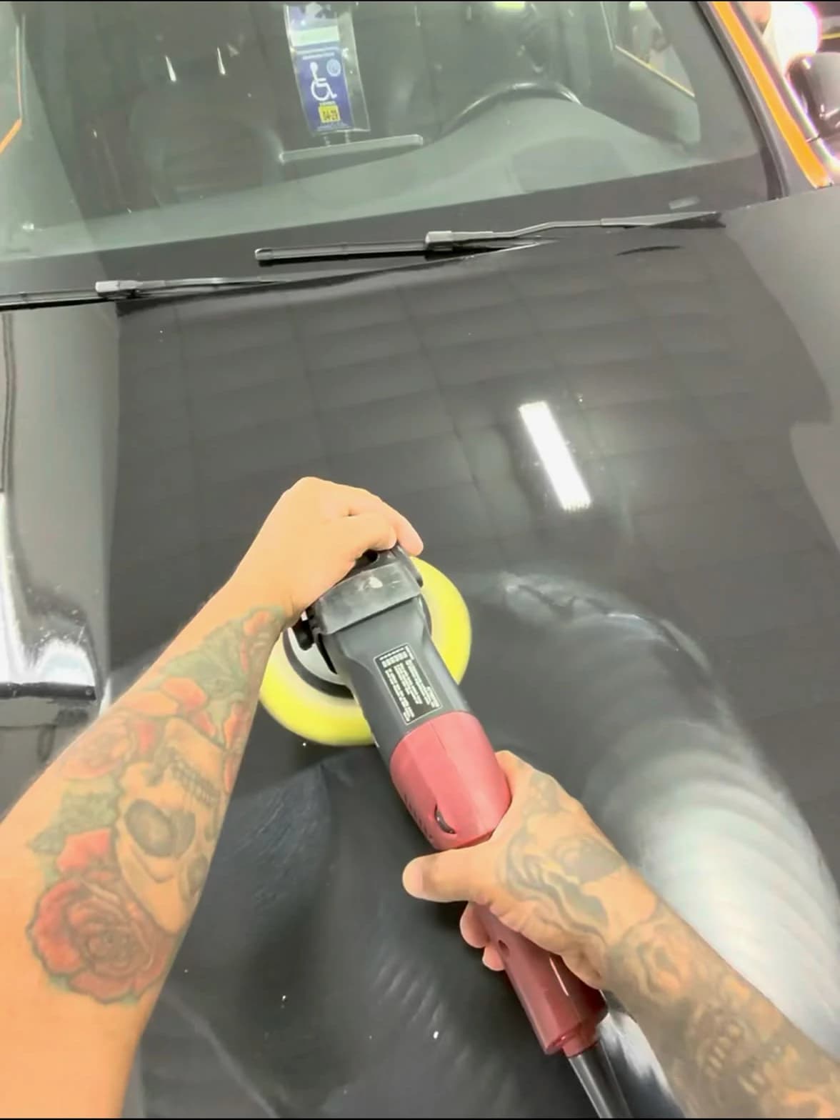 Paint correction in progress on a black hood